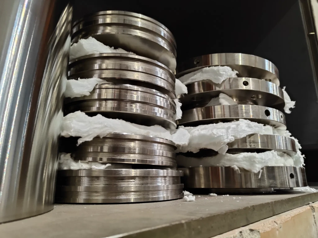 Metal components positioned in the oven, awaiting the start of the heat treatment. These components, previously coated with high-phosphorus electroless nickel, are ready to undergo the thermal strengthening process. Once the treatment is complete, these pieces will ensure optimal strength.