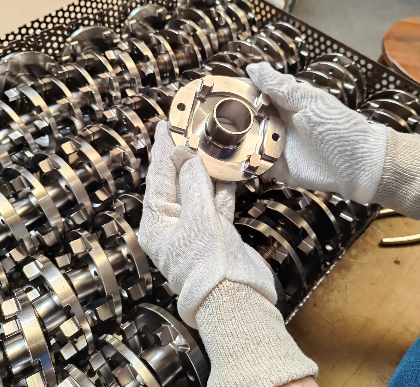 Aluminum nickel-plated pieces, carefully handled with white gloves, as part of a final visual inspection before their ultimate packaging. The high-phosphorus electroless nickel finish not only provides corrosion protection but also an elegant aesthetic. This meticulous inspection ensures compliance and impeccable quality of the pieces before their release.