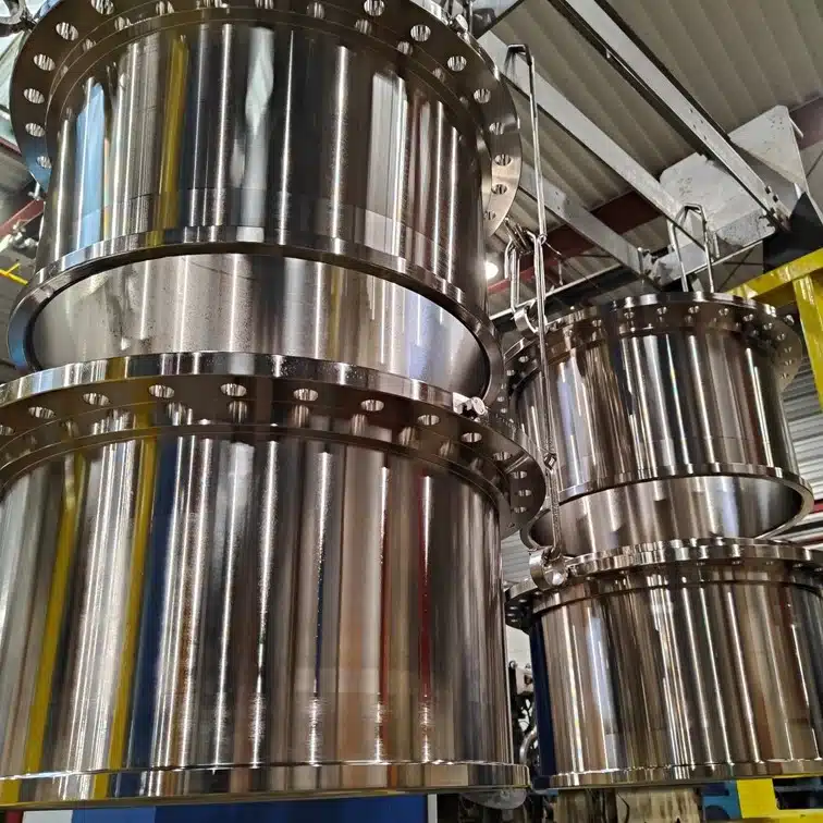 Grandi componenti cilindrici metallici in un’officina industriale.