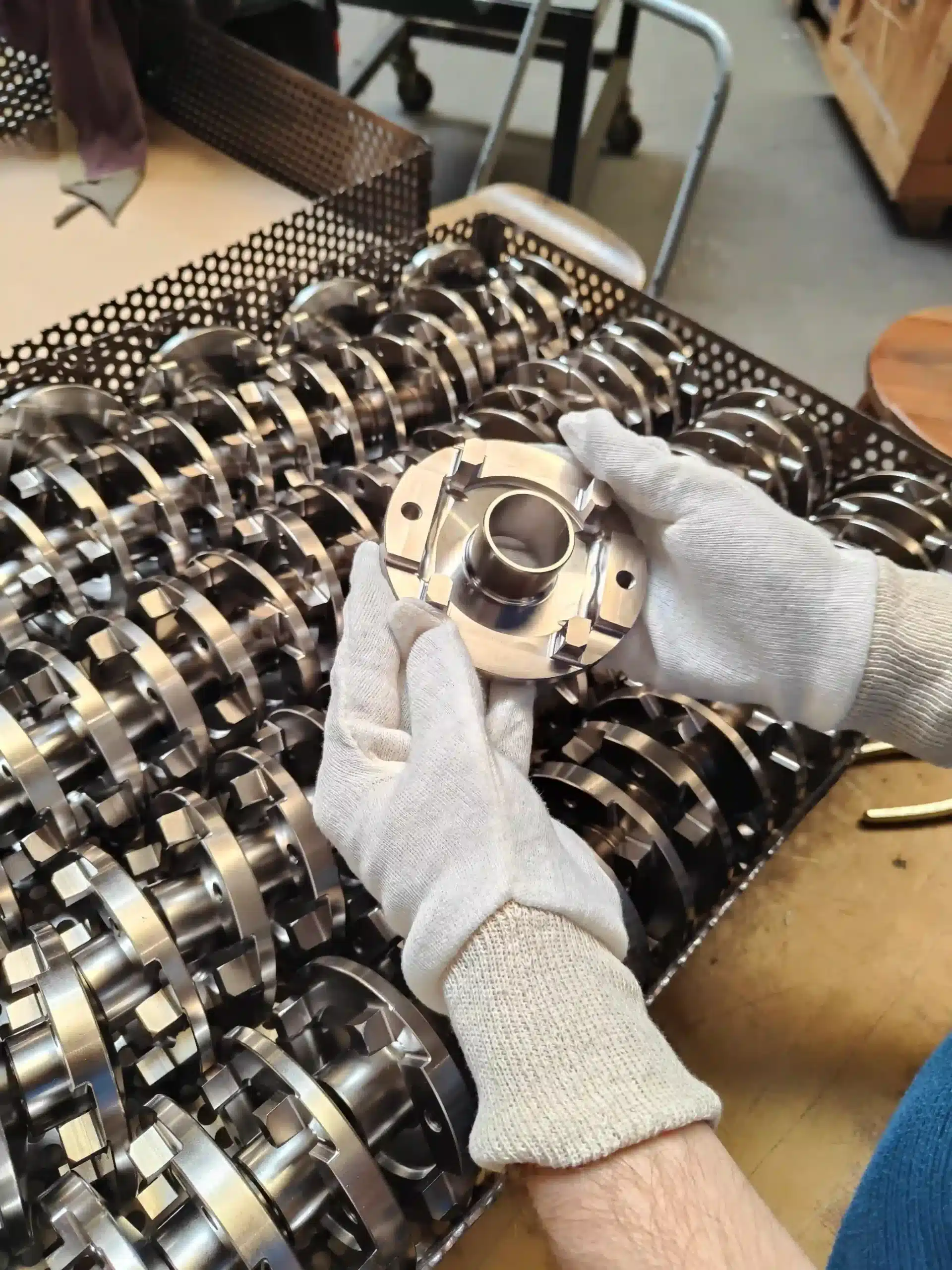 Metal part handled with gloves above a set of industrial components